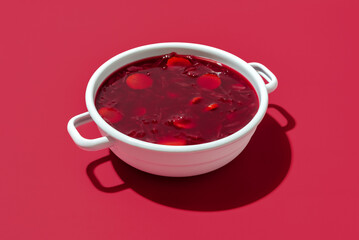 Red beet soup bowl on a red background. Bowl of the Ukrainian borscht.
