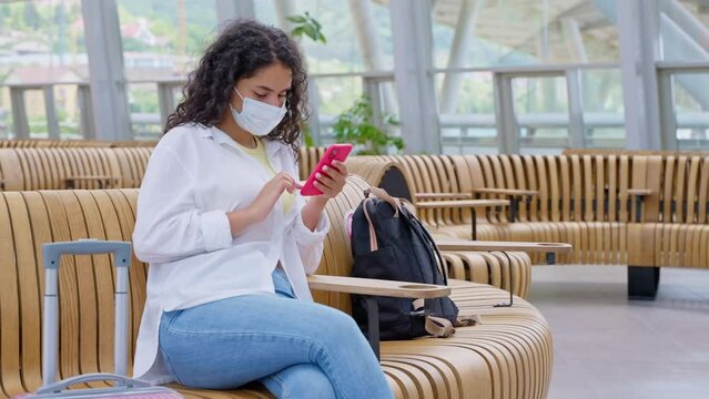 Woman passenger with smartphone in departure lounge of the station