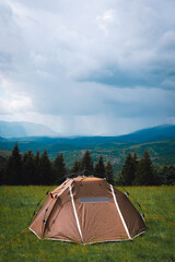A brown tourist tent, with a quick-set system, stands on top of a mountain. A wonderful warm summer morning, the concept of freedom and travel. Vertical photo