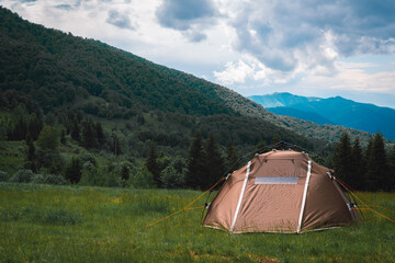 A brown tourist tent, with a quick-set system, stands on top of a mountain. A wonderful warm summer morning, the concept of freedom and travel. Carpathians, Prislop Pass, Ukraine