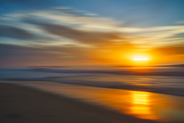 Fototapeta na wymiar Abstract seascape. Tranquil scene of empty sand beach at sunset. Golden waves, sun reflections, motion blur, copy space