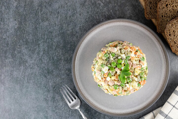 Traditional Russian olivier salad of pickled cucumbers, sausage, green peas, potatoes and mayonnaise. Top view, copy space.
