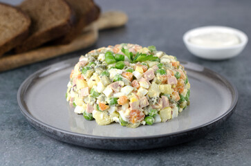 Traditional Russian olivier salad of pickled cucumbers, sausage, green peas, potatoes and mayonnaise. Russian New Year and Christmas food. 
