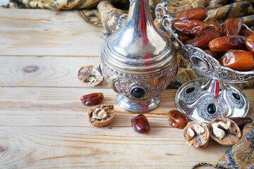 Obraz na płótnie Canvas Eastern sweets with nuts, candy, tea in glass, metal vase, tea, dates on wooden background