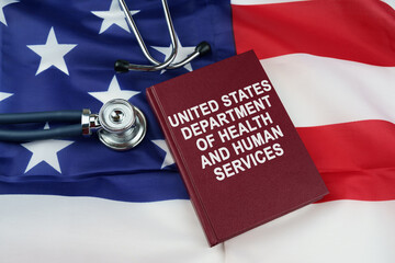 On the US flag lies a stethoscope and a book with the inscription -United States Department of...
