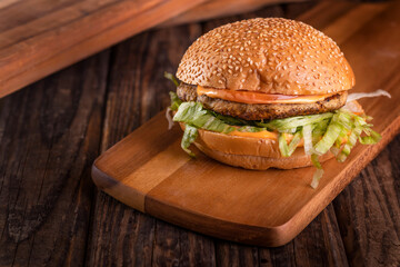 Grilled Chicken burger isolated on cutting board top view on dark background american fast food