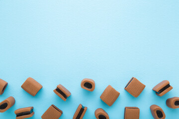 Brown jelly gummy candies with dark chocolate on light blue table background. Pastel color. Sweet...