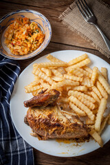 Roasted chicken with french fries on a plate.