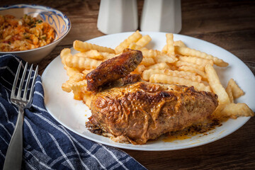 Roasted chicken with french fries on a plate.