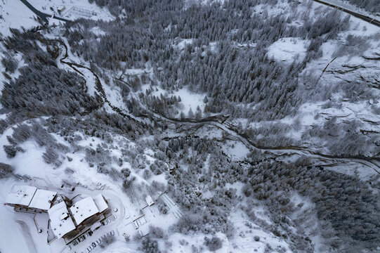 Aerial View Of Snow-covered Pines In The Alps, Snow Falling On The Mountains And Frozen Lake In The Mountains 