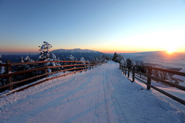 Amazing view of winter sunset over a slope in Poiana Brasov ski resort in Transylvania, Romania. Bucegi mountains in background.