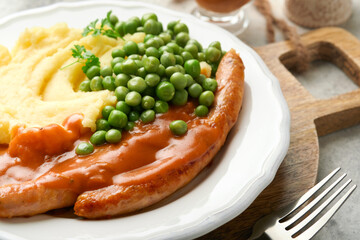 Bangers and mash. Grilled sausages with mash potato and green pea on white plate on grey background. Traditional dish of Great Britain and Ireland. BBQ beef sausages. Top view.