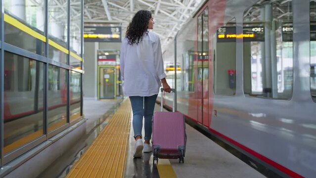 Girl with suitcase walking on the station platform