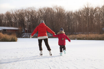 grandmother and child granddaughter  ice skating on a frozen lake  in winter nature. Enjoying the...