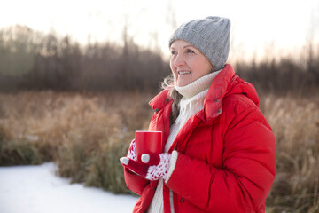 portrait of a cheerful senior woman with hot Cocoa Drink in winter nature. Enjoying the little...