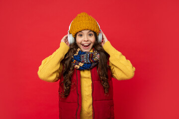 amazed child listen music in headphones. kid wear warm clothes. express positive emotion.