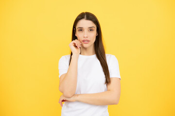 Fototapeta premium Pretty joyfully female model looking with satisfaction. Studio portrait of looking beautiful woman isolated against yellow background.