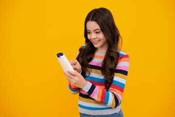 Naklejka premium Teen child girl with shampoo bottle or shower gel isolated on yellow background. Kids hair cosmetic product. Happy teenager, positive and smiling emotions of teen girl.