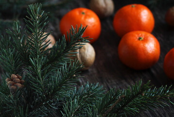 Fototapeta na wymiar New Year's layout of tangerines, spruce branches and walnuts on a wooden background