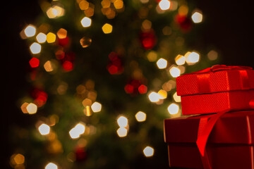 Duas caixas de presente, vermelhas, com um laço de fita, com uma árvore de Natal ao fundo.