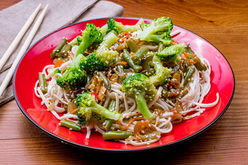fried wheat noodles with vegetables on wooden table