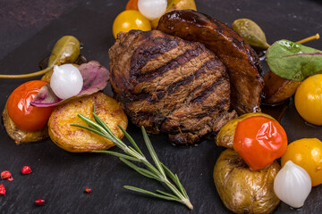grilled steak filet Mignon with mini potatoes on dark stone plate macro close up - 552170358