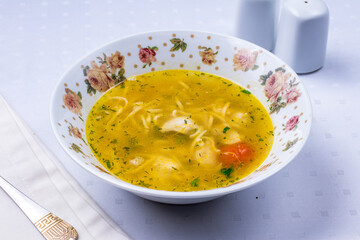 Chicken soup bouillon in a plate on white table