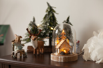 Glass cloche with a wooden house inside and golden lights. Christmas decoration at home. Festive...
