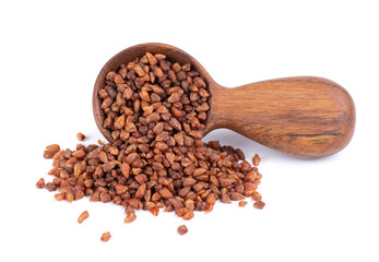 Buckwheat tea in wooden spoon, isolated on white background. Whole roasted buckwheat grains. Fagopyrum tataricum.