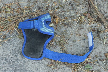 one empty pistol holster with a belt made of black leather and blue fabric lies on the gray sand in...