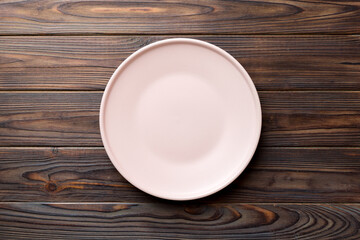 Top view of empty pink plate on wooden background. Empty space for your design