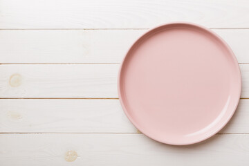 Top view of empty pink plate on wooden background. Empty space for your design