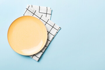 Top view on colored background empty round yellow plate on tablecloth for food. Empty dish on napkin with space for your design