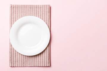 Top view on colored background empty round white plate on tablecloth for food. Empty dish on napkin with space for your design