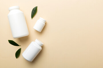 supplement pills with medicine bottle health care and medical top view. Vitamin tablets. Top view mockup bottle for pills and vitamins with green leaves, natural organic bio supplement, copy space