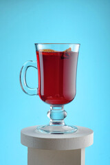 Mulled wine with dried orange, cinnamon sticks and cloves isolated on a blue background. Winter traditional alcoholic hot drink based on wine.