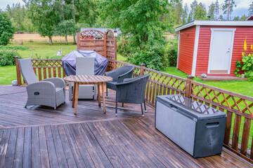 Heavy rain at wooden terrace with summer chairs, wooden table. Blurry green forest at background....