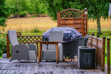 Heavy rain at wooden terrace with summer chairs, wooden table, grill covered against of rain....
