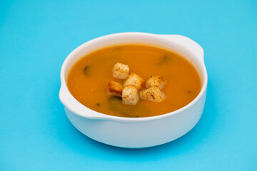 vegetable soup with crackers in white bowl on blue