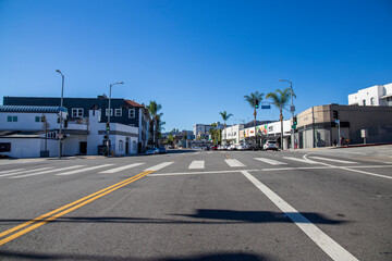 Fototapeta na wymiar a large intersection at Ivar Avenue and Yucca Street in Hollywood with lush green palm trees, a green traffic signal, parked cars and shops with a clear blue sky in Los Angeles California USA