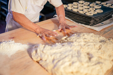 Manos de un hombre trabajando con masa y harina de trigo en una panaderia. Manos de repostero. 