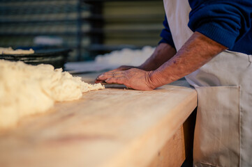 Manos de un hombre trabajando con masa y harina de trigo en una panaderia. Manos de repostero. - obrazy, fototapety, plakaty
