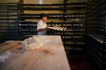 Retrato de un hombre adulto trabajando en una panaderia. Hombre haciendo pan, pasteles, galletas, pizza artesanales.  - obrazy, fototapety, plakaty