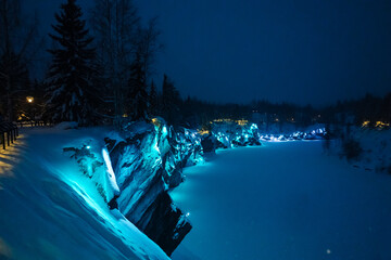 Beautiful panoramic view of night park with colorful lights on winter forest and rocks, Ruskeala,...