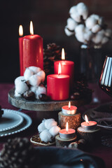Rustic table decor for Christmas or New Year family dinner. Centrepiece with red candle, dry orange, cone, cinnamon, anise. Zero waste eco-friendly home. Cozy atmosphere, dark background. Close up