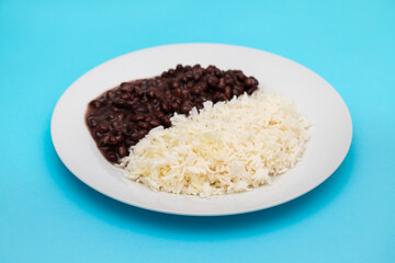 Black beans and boiled rice on white dish.