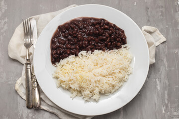 Black beans and boiled rice on white dish.