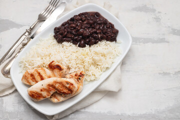 Healthy food with chicken breast, beans and rice on a white plate.