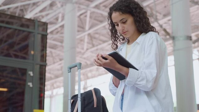 Young woman traveler with tablet computer at the station