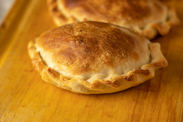 Extreme close up of baked Argentinian empanadas on a board.